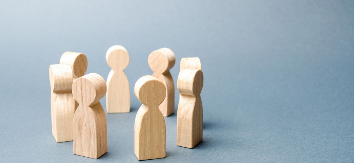 People stand in a circle on a gray background. Wooden figures of people. A circle of people. discussion, cooperation, cooperation. Communication. Business team, teamwork, team spirit. Selective focus